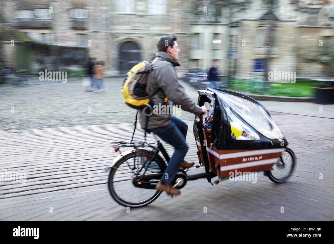 A man and his child ride their cargo bike through central Cambridge