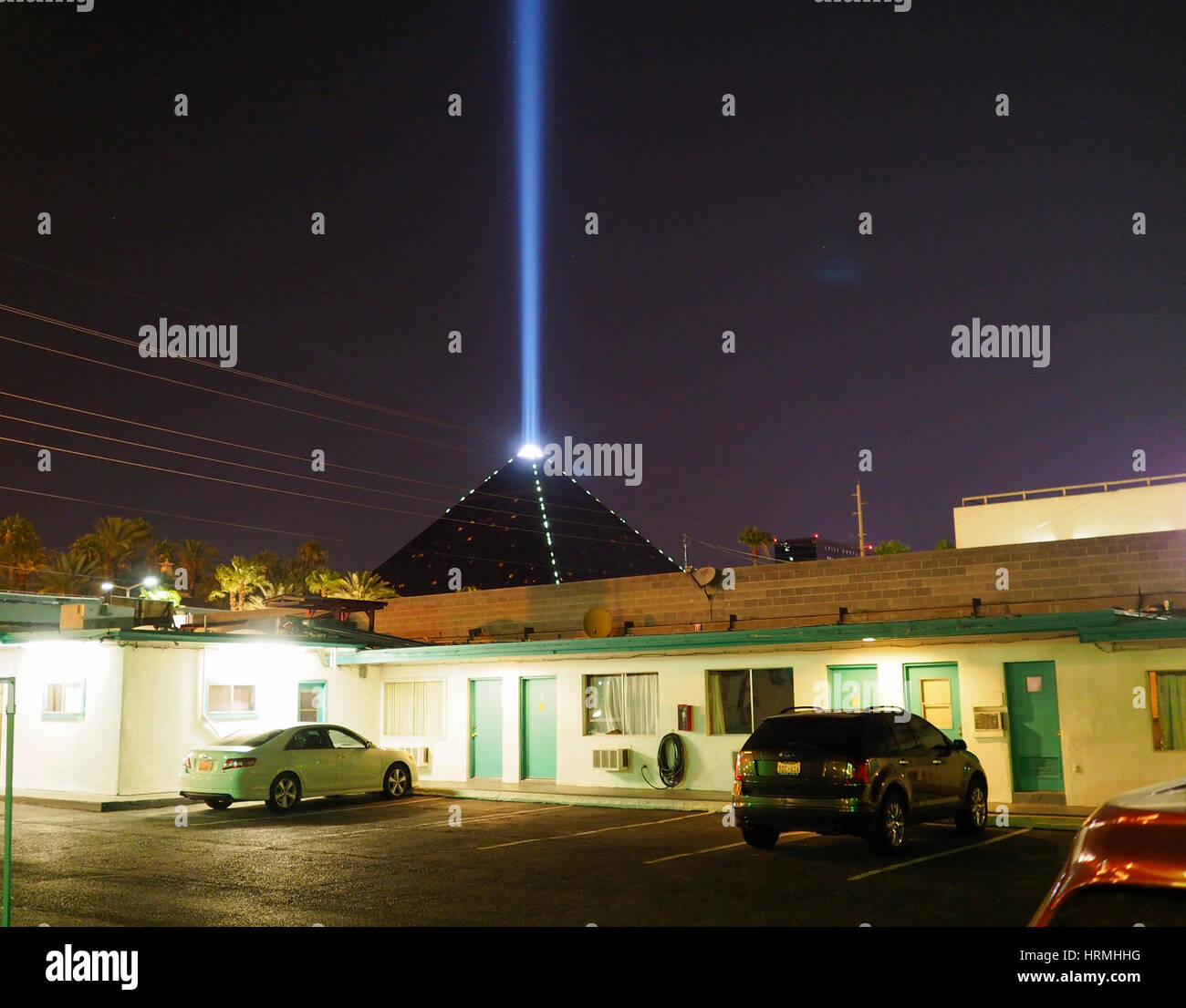 The bright light beam from the top of the 'Luxor' casino and hotel is visible in the Las Vegas sky behind the parking lot of a budeg motel far off the Stock Photo