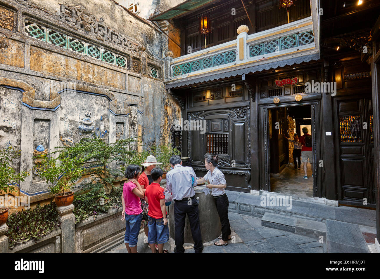 Tourists with local guides in the open courtyard of the Old House of Tan Ky. Hoi An Ancient Town, Quang Nam Province, Vietnam. Stock Photo
