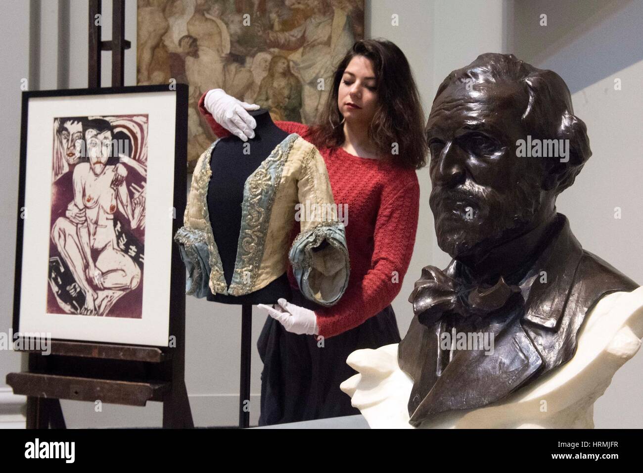 A member of staff adjusts an Italian cream and silver tinsel brocade, 'bodice of a theatre costume', c.1750 (centre), during a press call in London ahead of the Victoria and Albert Museum's Major autumn exhibition: Opera: Passion, Power and Politics. Stock Photo