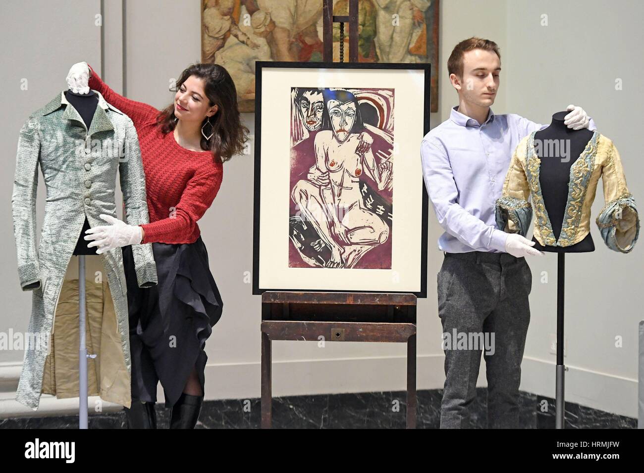 Members of staff adjust (left to right) a pale blue velvet French coat, c.1785-1790, 'The Melancholic Girl' by Ernst Ludwig Kirchner, 1928, and an Italian cream and silver tinsel brocade, 'bodice of a theatre costume', c.1750, during a press call in London ahead of the Victoria and Albert Museum's Major autumn exhibition: Opera: Passion, Power and Politics. Stock Photo