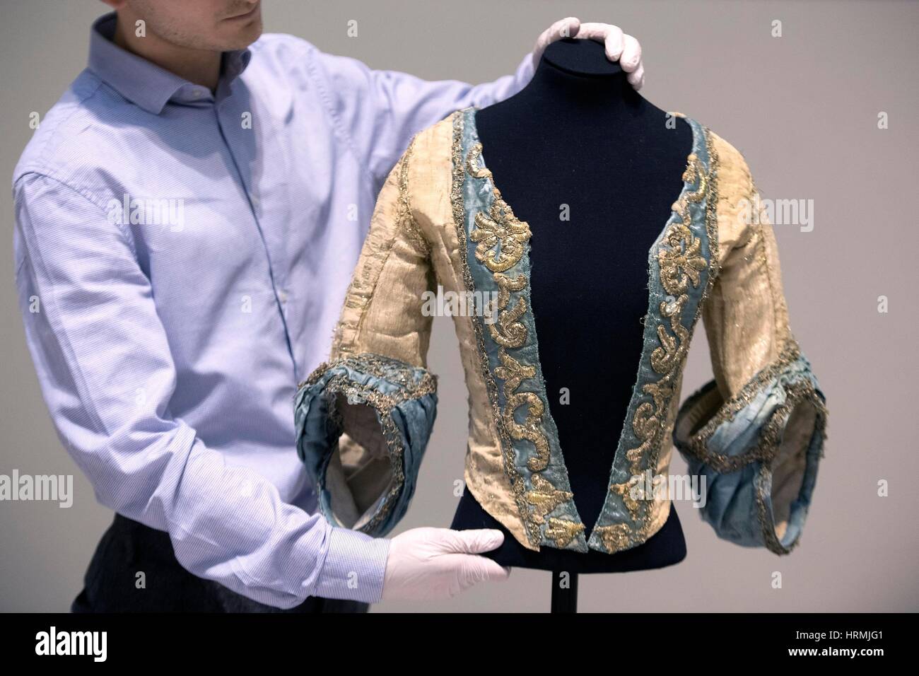 A member of staff adjusts an Italian cream and silver tinsel brocade, 'bodice of a theatre costume', c.1750, during a press call in London ahead of the Victoria and Albert Museum's Major autumn exhibition: Opera: Passion, Power and Politics. Stock Photo