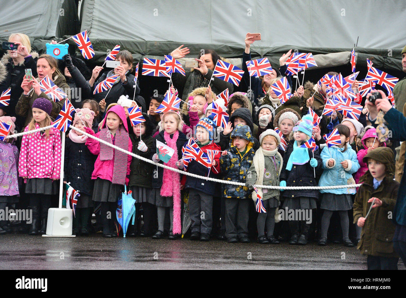 Children wave flags during a visit by Queen Elizabeth II to The Royal Welsh Regiment at Lucknow Barracks in Tidworth, Wiltshire, to mark St David's Day. Stock Photo