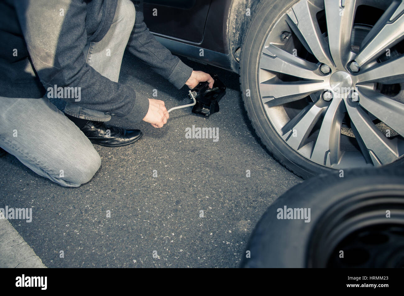 Man picks up vehicle with the lifting jack to change a tire Stock Photo