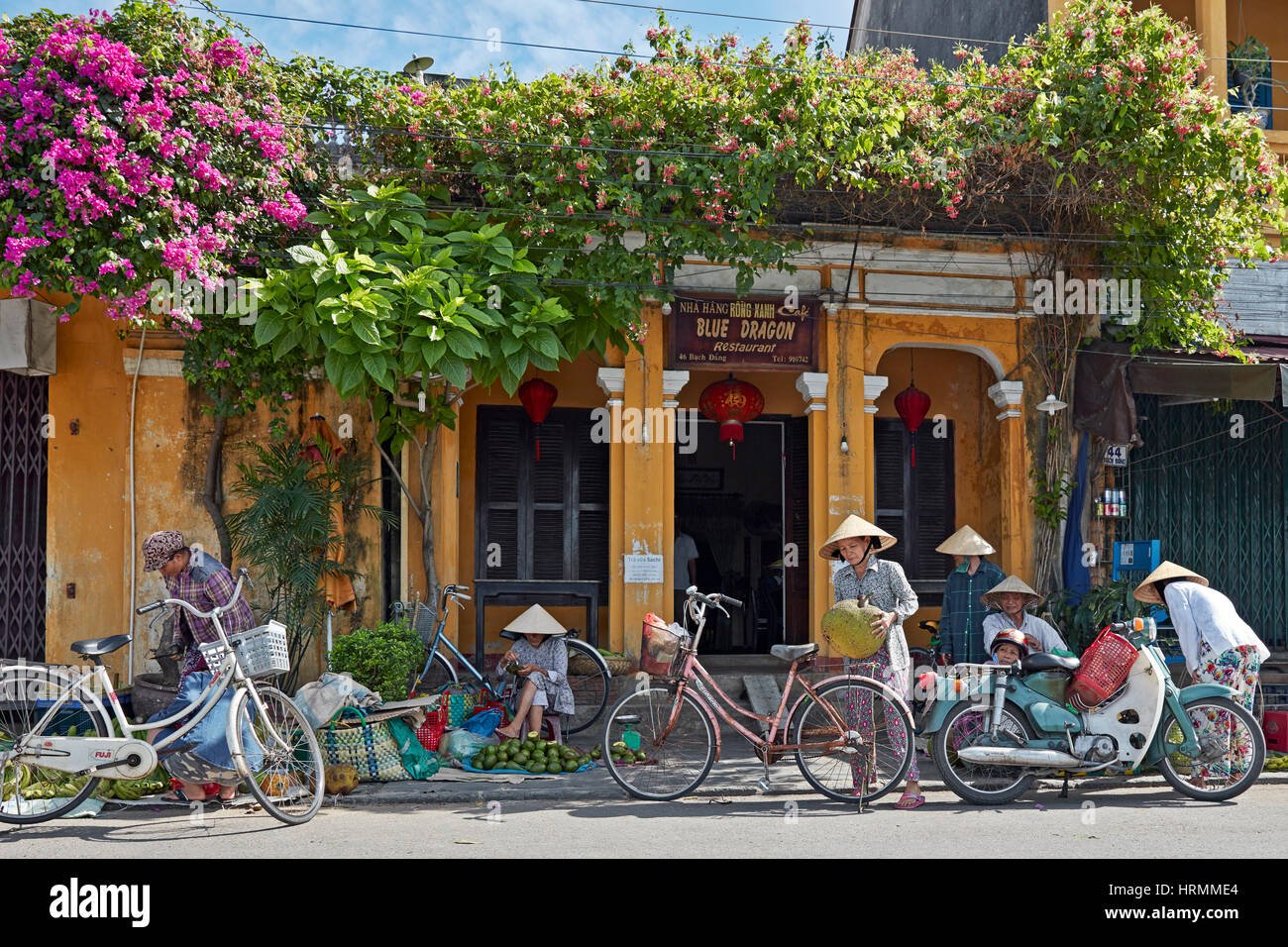 Local fruit vendors and their customers doing daily business in Hoi An Ancient Town. Quang Nam Province, Vietnam. Stock Photo