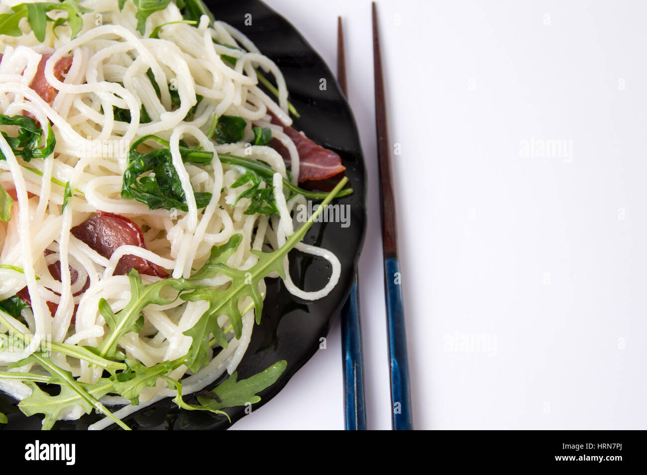 Pasta with prosciutto and arugula vegetable on a plate on white Stock Photo