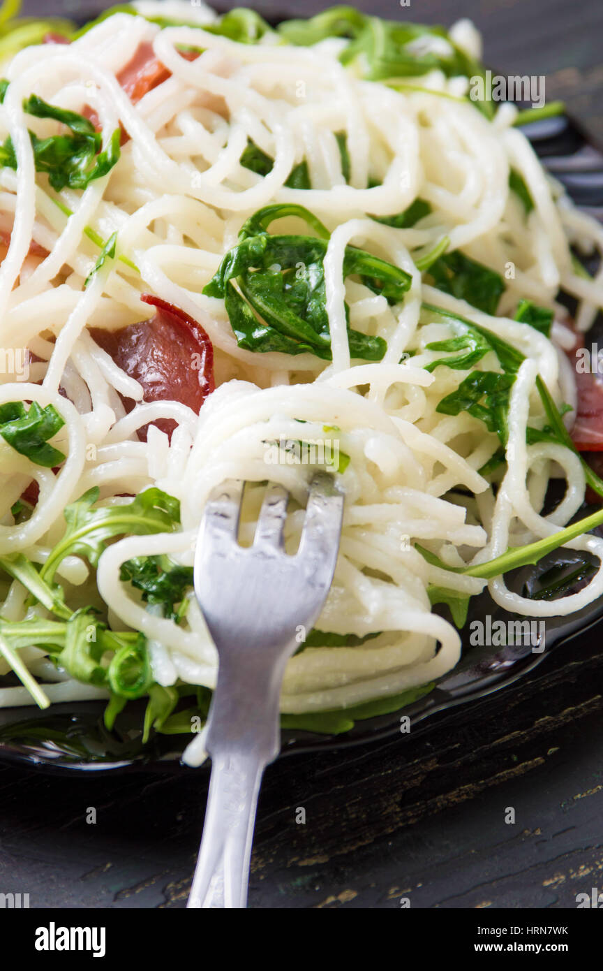 Pasta with prosciutto and arugula vegetable served on a plate Stock Photo