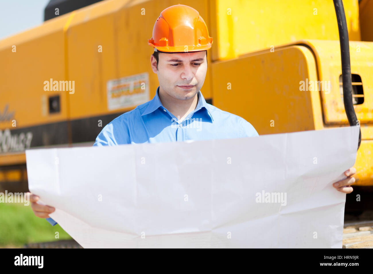 Architect in a construction site looking at a blueprint Stock Photo - Alamy