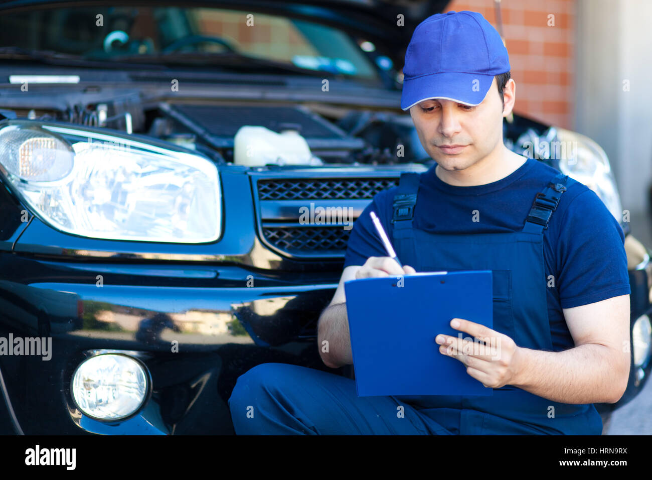 Mechanic writing on clipboard Stock Photo - Alamy