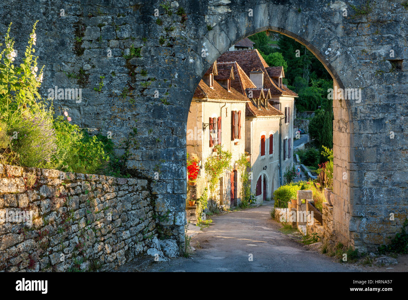 Setting sunlight on homes at entry gate to Saint-Cirq-Lapopie, Lot Valley, Occitanie, France Stock Photo
