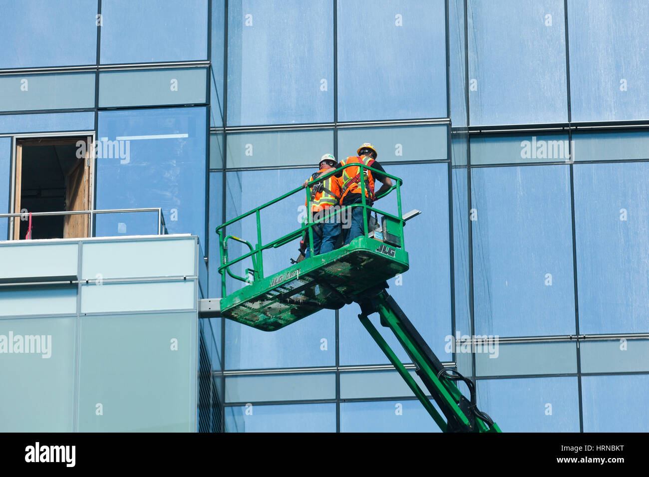 Men working on building exterior atop a boom lift - USA Stock Photo