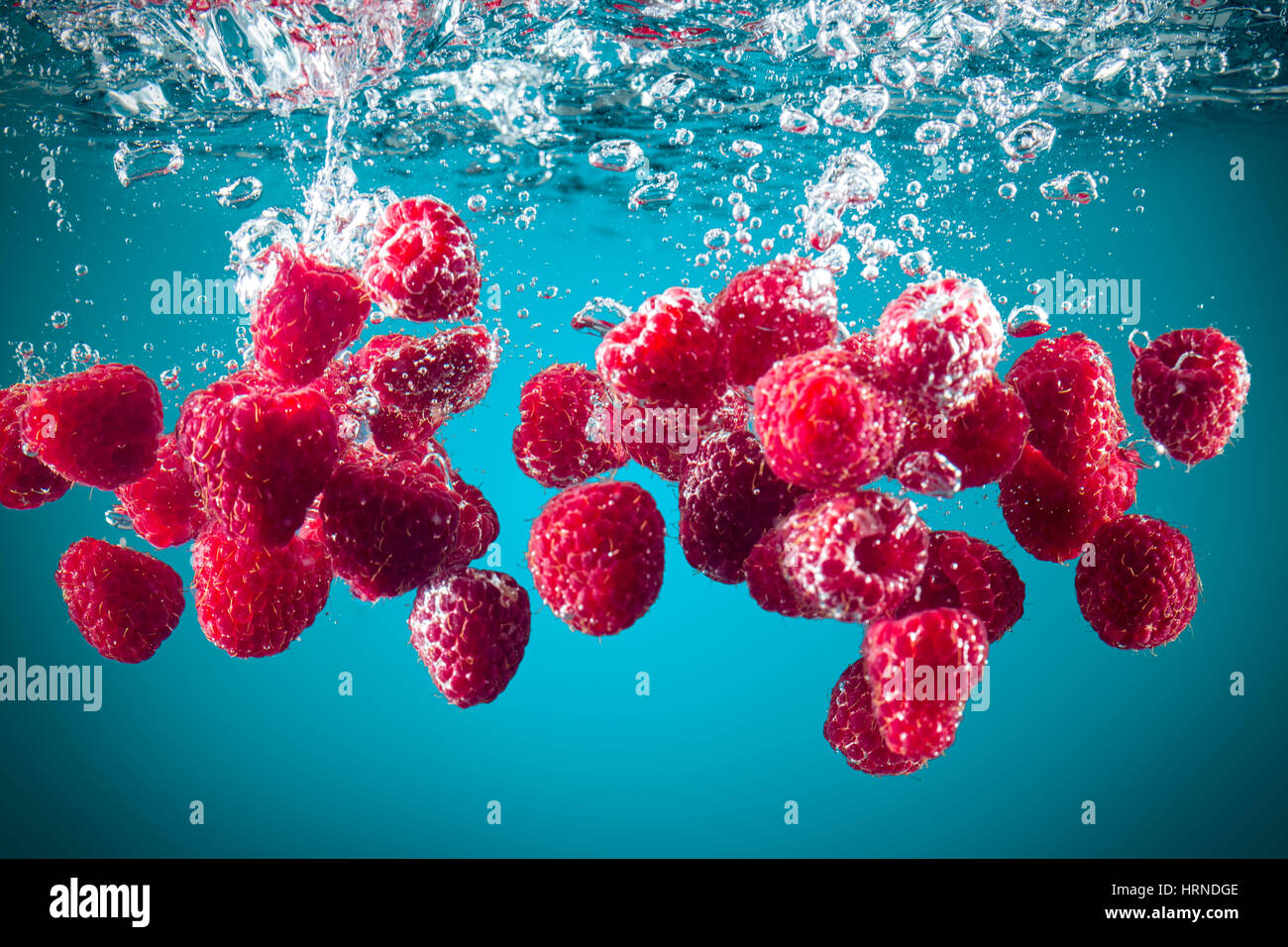 Fresh raspberries dropped into water background Stock Photo - Alamy