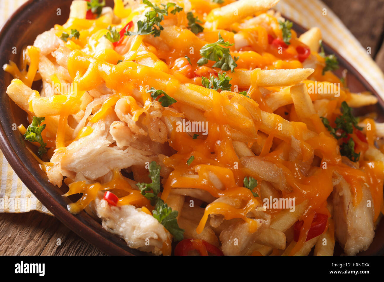 Spicy french fries with cheddar cheese, chili pepper and chicken meat macro on a plate. horizontal Stock Photo
