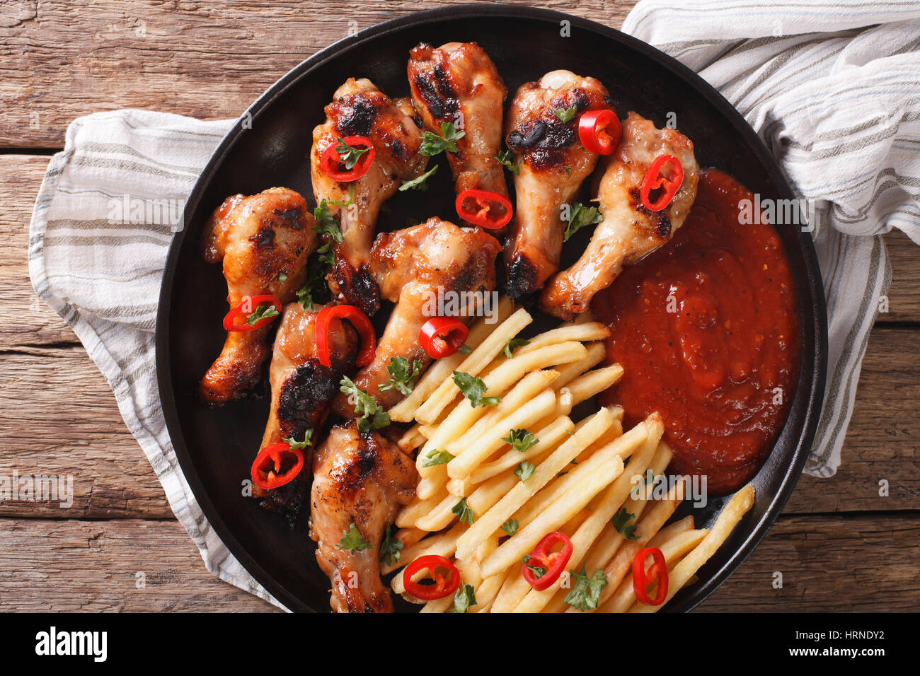 Spicy BBQ chicken wings with french fries and sauce on a plate close-up