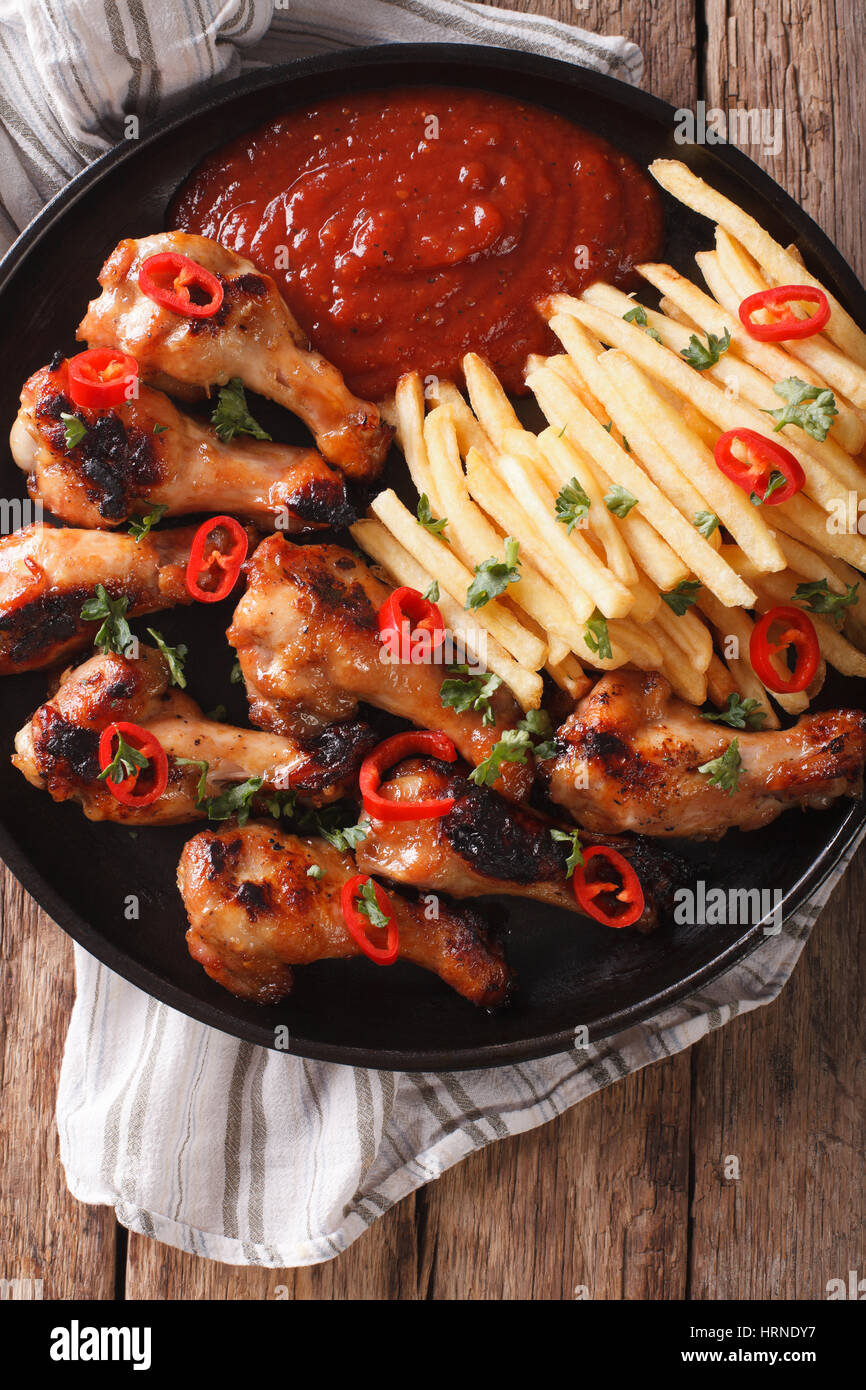 Grilled chicken wings with french fries and ketchup on the table close-up. vertical view from above Stock Photo