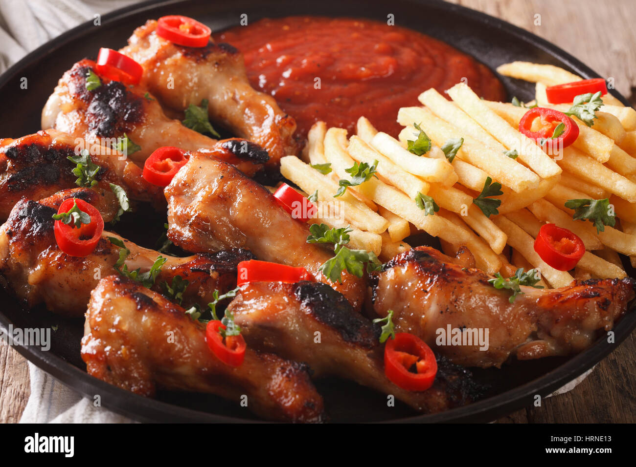 Roasted chicken wings with french fries and ketchup on a plate close-up. horizontal Stock Photo