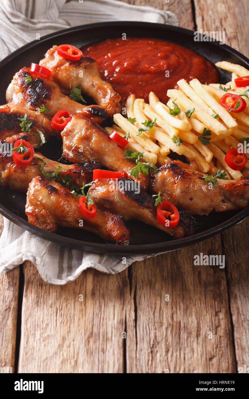 Grilled chicken wings with french fries and ketchup on the table close-up. vertical Stock Photo
