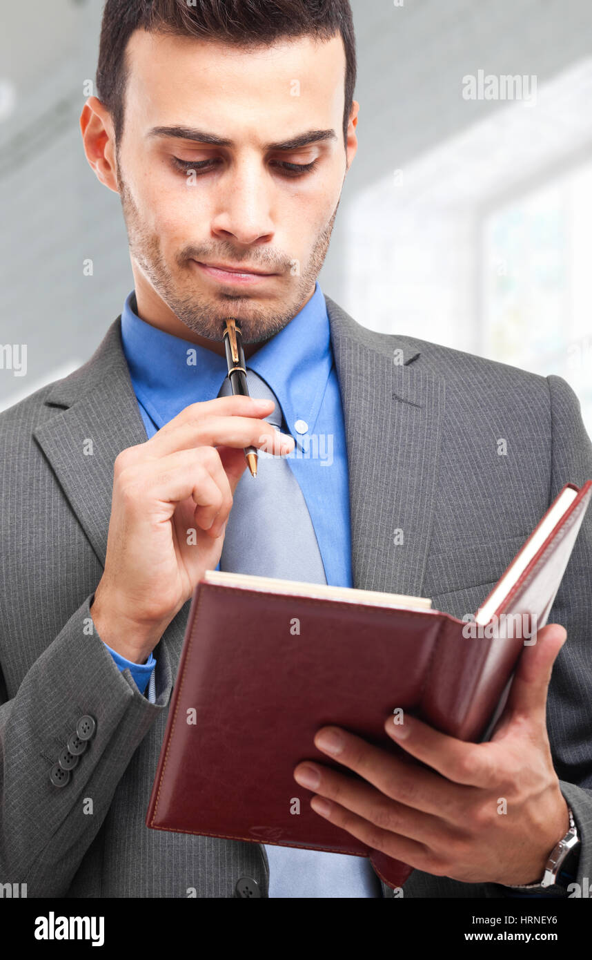 Thoughtful businessman writing on his agenda Stock Photo - Alamy