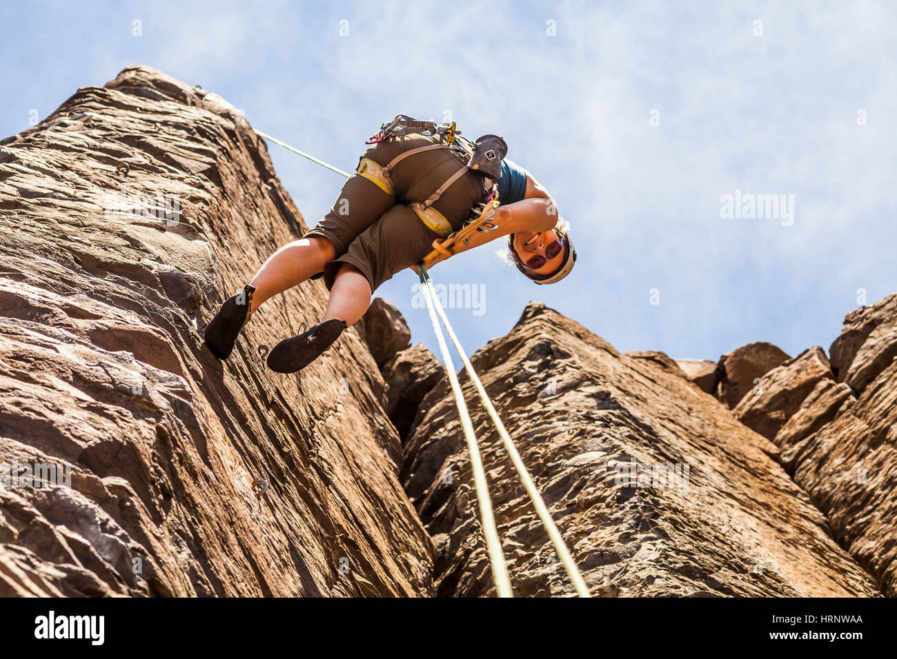 Looking up at a woman who is rappelling down from a rock climb at