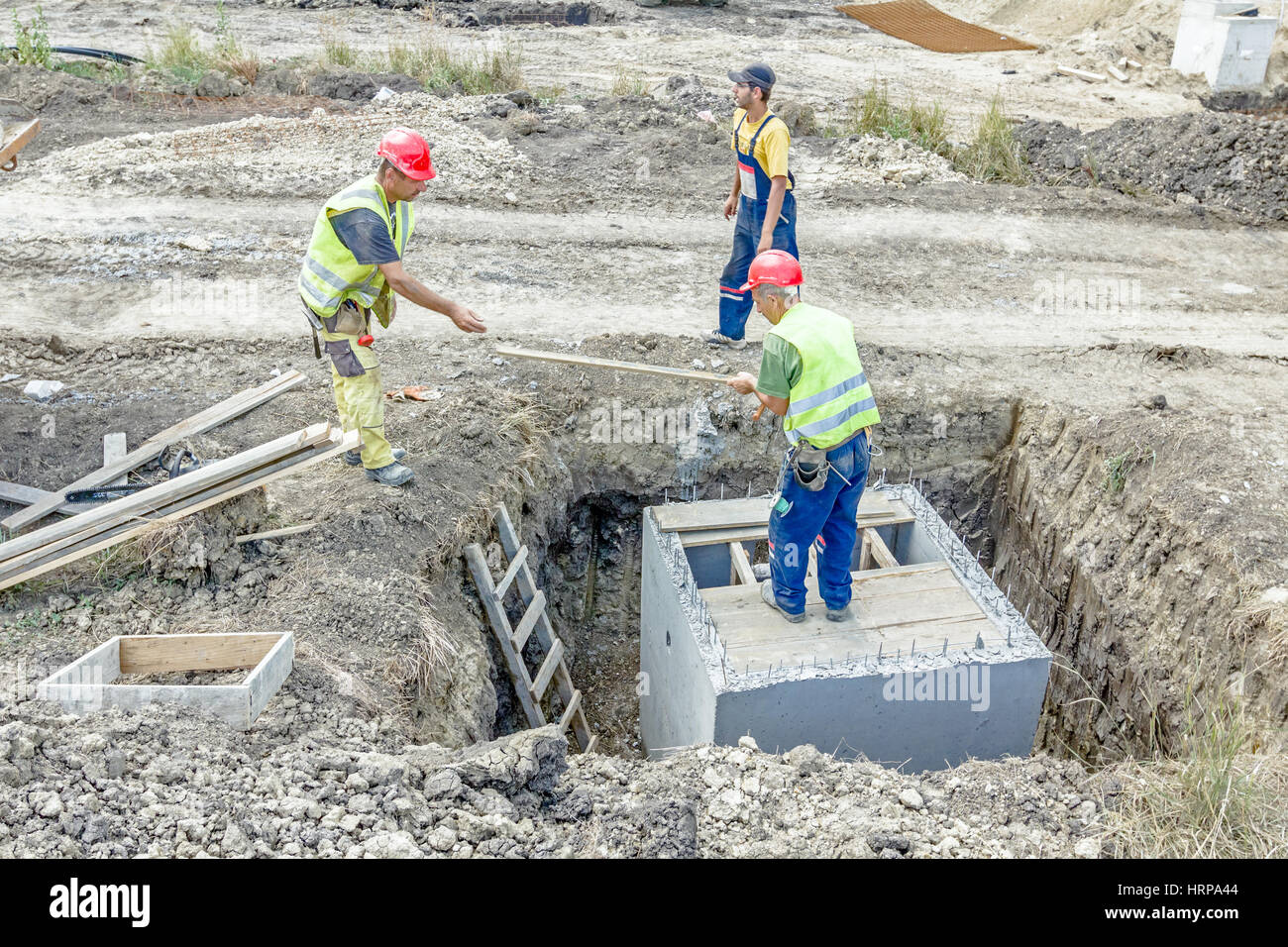 Zrenjanin, Vojvodina, Serbia - June 29, 2015: Construction workers are preparing wooden mold for concrete pouring slab on utility hole. Stock Photo