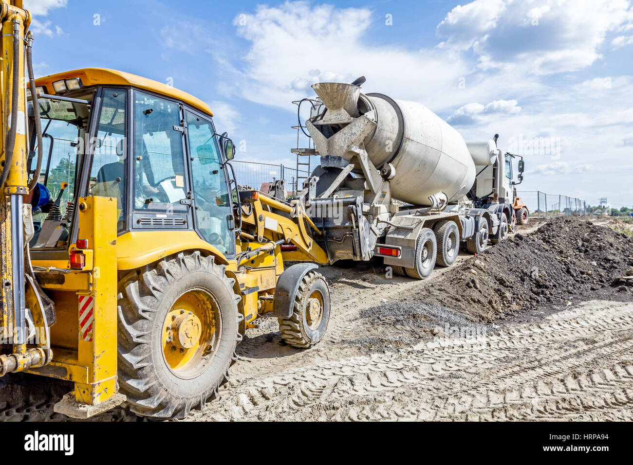 Concrete mixer truck is pouring fresh concrete into excavator bucket at  construction site Stock Photo - Alamy