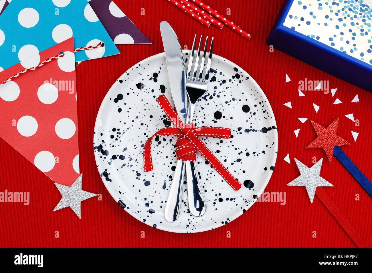 Party and celebration table setting with gift box on red tablecloth background Stock Photo