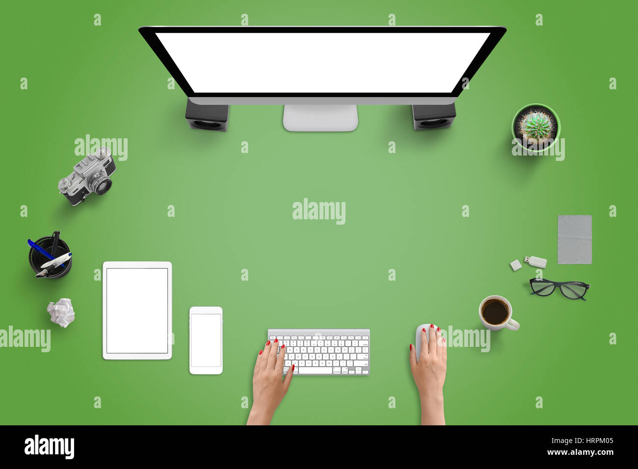 Top view of studio desk with modern devices. Computer display, tablet and mobile phone. Green desk with free space for text. Stock Photo