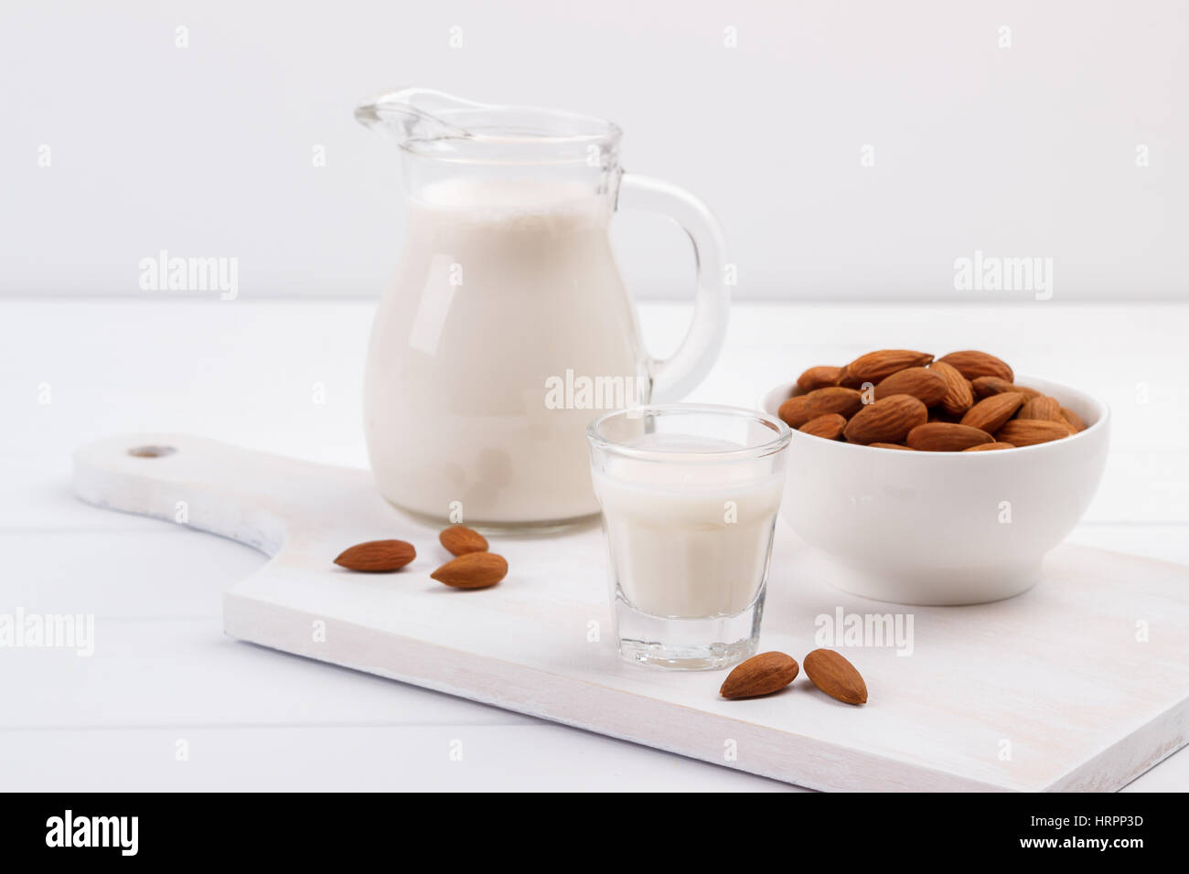 Free Photo  Some milk carafe with almonds on white wooden background, side  view.