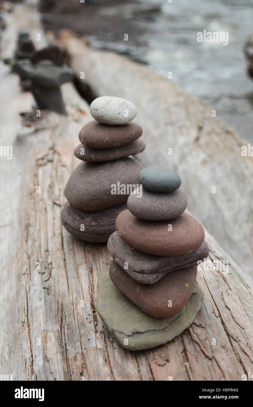 Two stacks of rocks, or cairns, on a log next to water Stock Photo Alamy