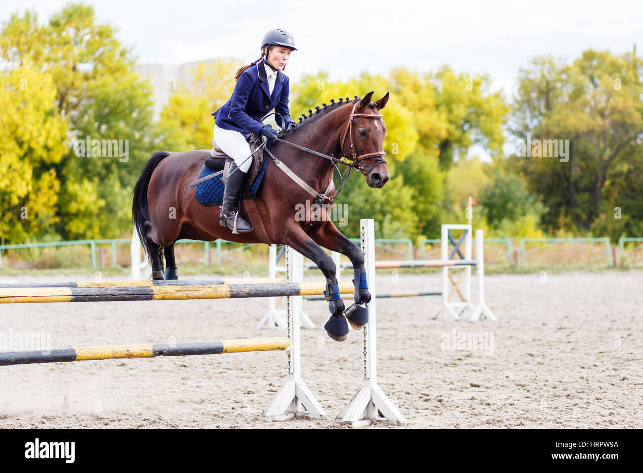 Young horseback sportswoman jumping over obstacles on show jumping