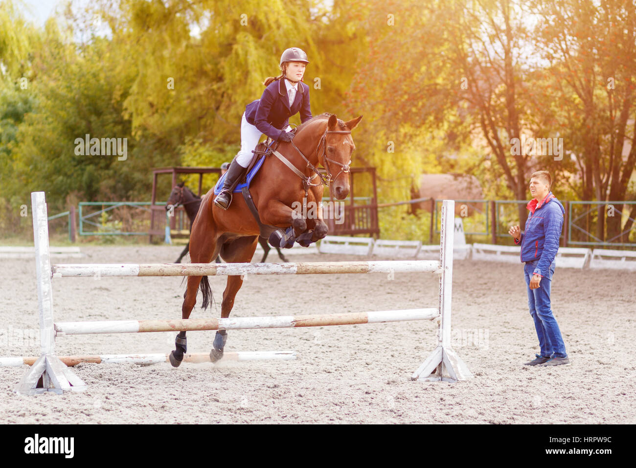 Young horseback sportswoman jumping over obstacles on show jumping