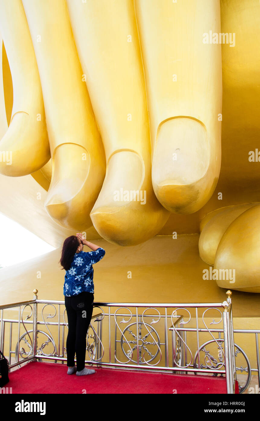 Asian thai old woman praying and touch fingers pointing down to earth
