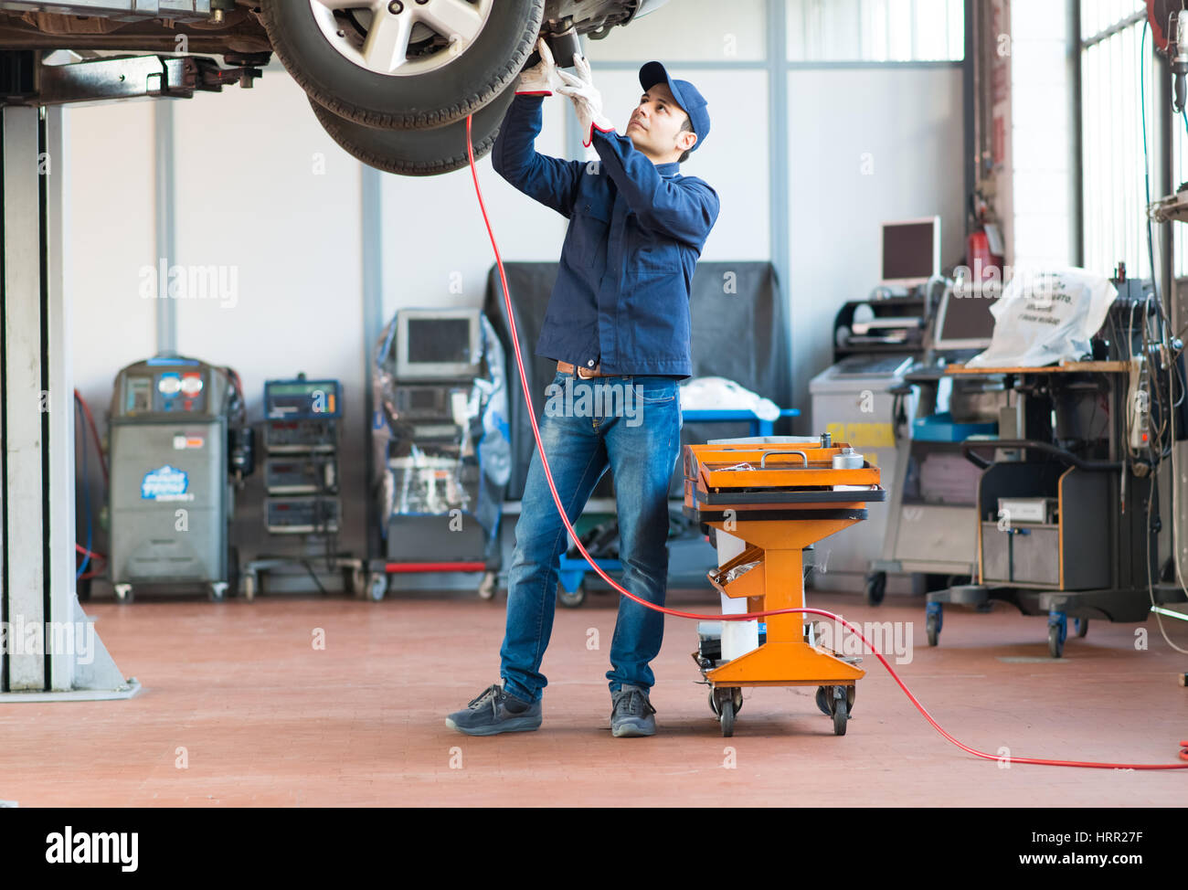Mechanician changing car wheel in auto repair shop Stock Photo - Alamy
