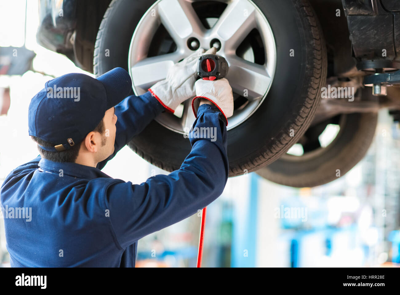 Mechanician changing car wheel in auto repair shop Stock Photo - Alamy