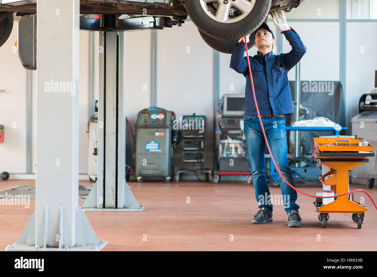 Mechanician changing car wheel in auto repair shop Stock Photo - Alamy