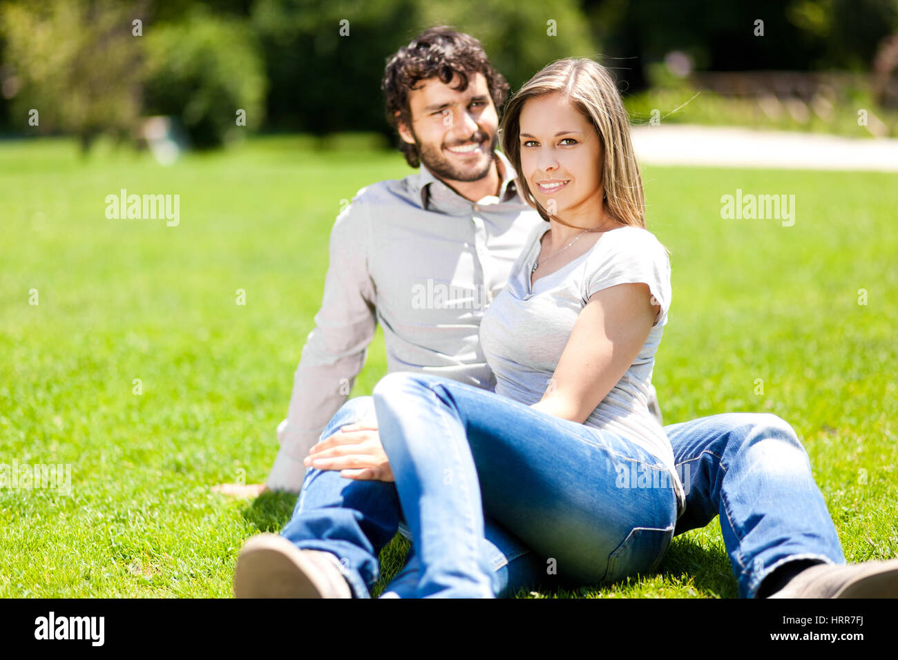 Young happy couple sitting in a park Stock Photo - Alamy