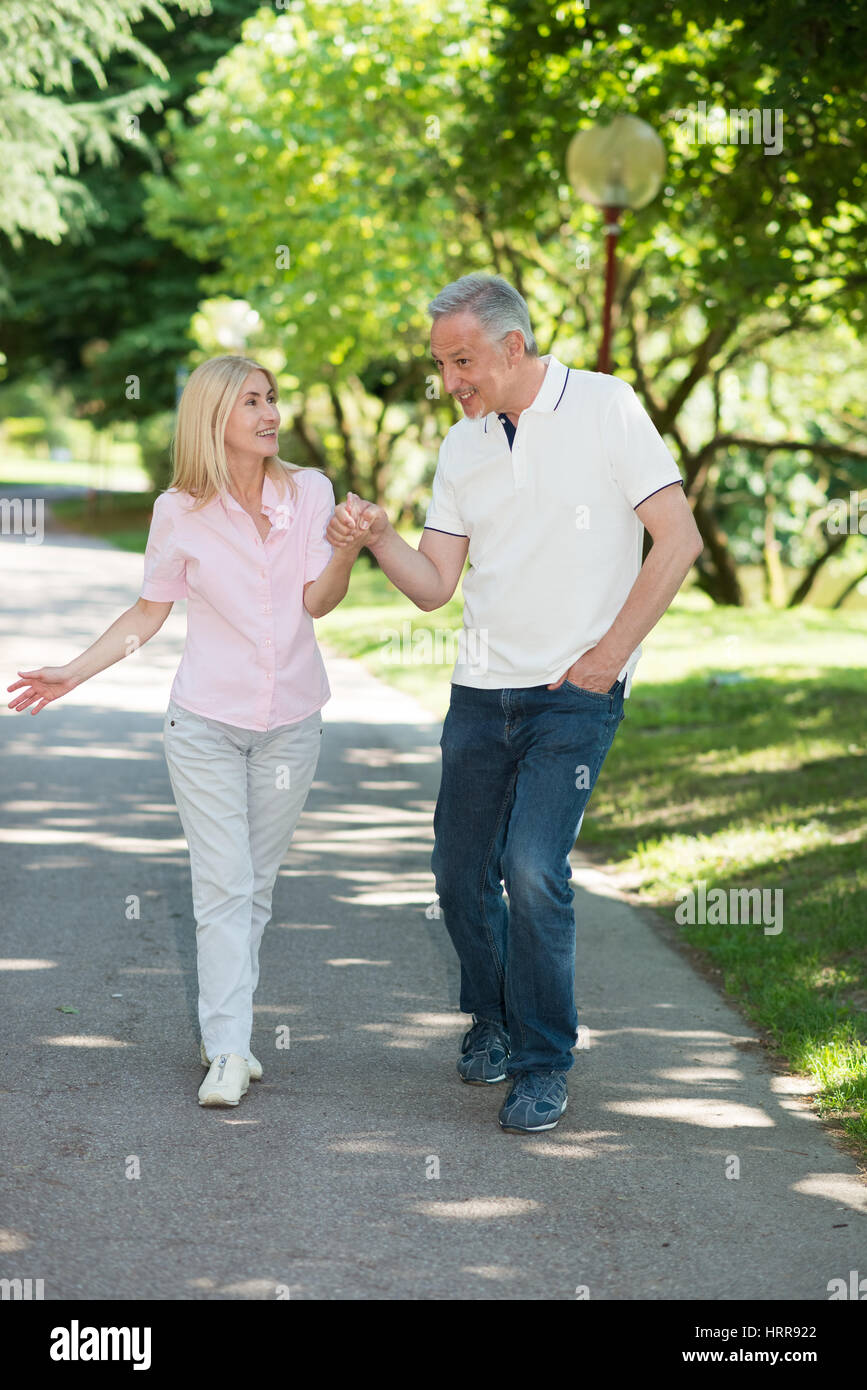 Happy mature couple walking in a park while holding hands Stock Photo ...