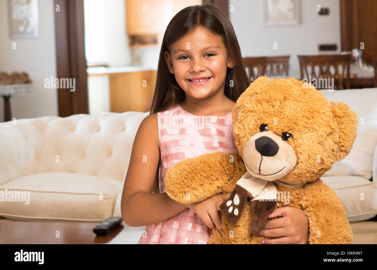 Smiling little girl holding a teddy bear at home Stock Photo - Alamy