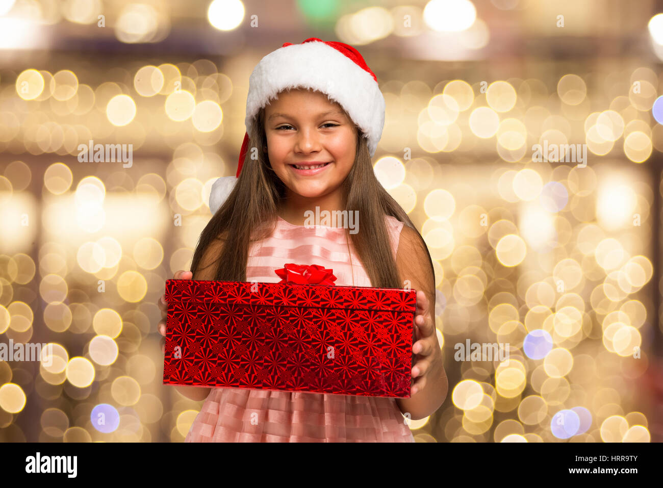 Smiling little girl holding a Christmas present Stock Photo - Alamy