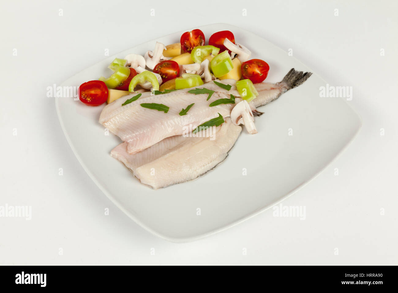 cleaned trout fillet on a white plate and fresh vegetables Stock Photo
