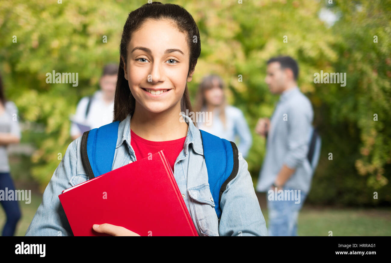 Smiling teenager student holding a book Stock Photo - Alamy