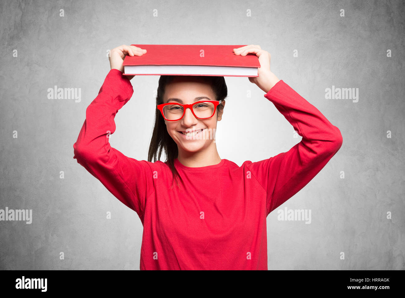Teenager student holding a book over her head Stock Photo - Alamy