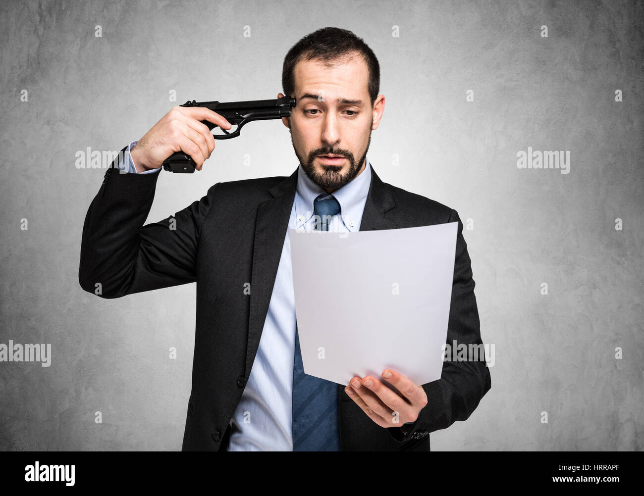 Businessman poining a gun to his head while reading bad news Stock Photo