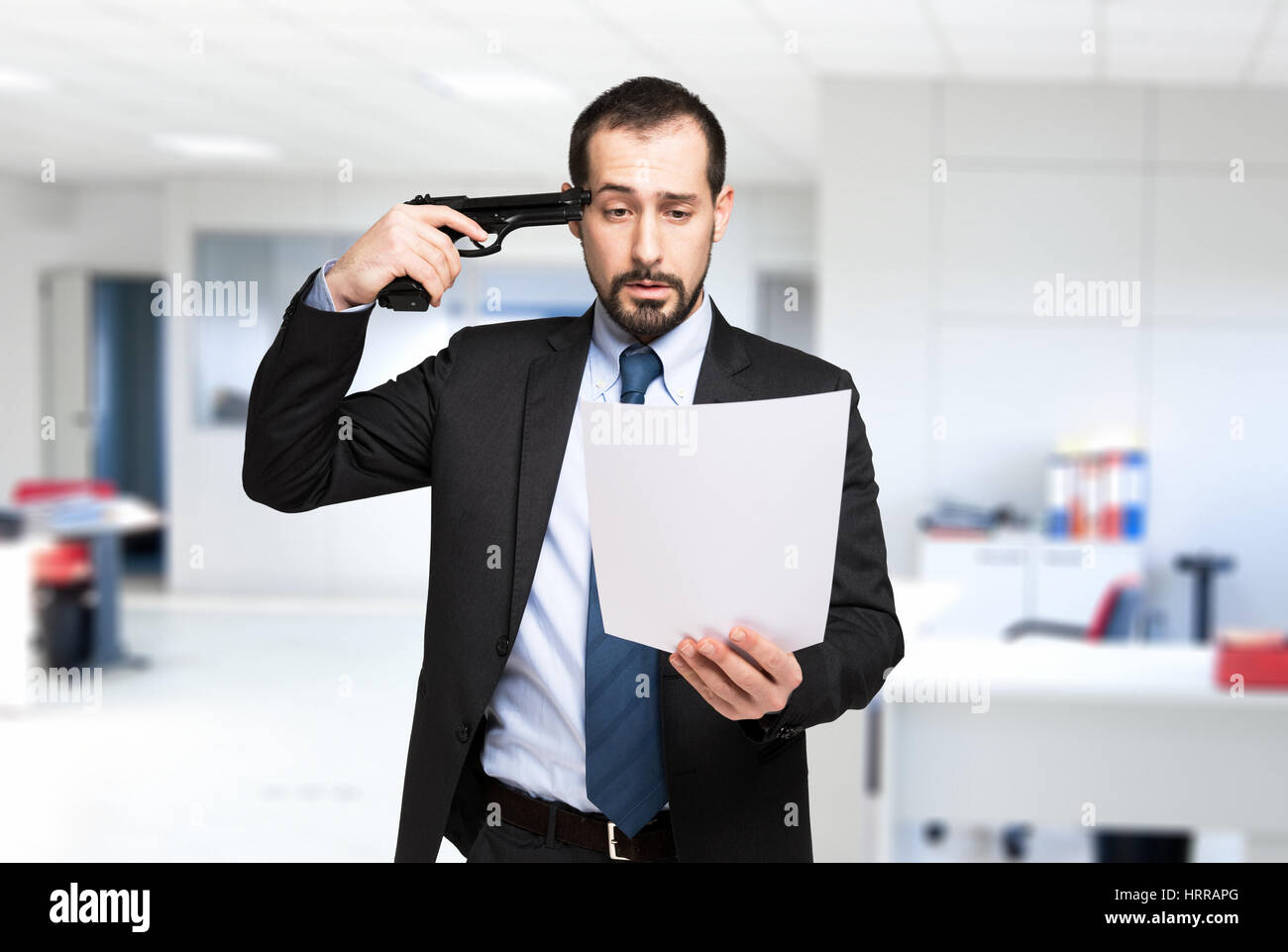 Businessman pointing a gun to his head while reading a document Stock Photo