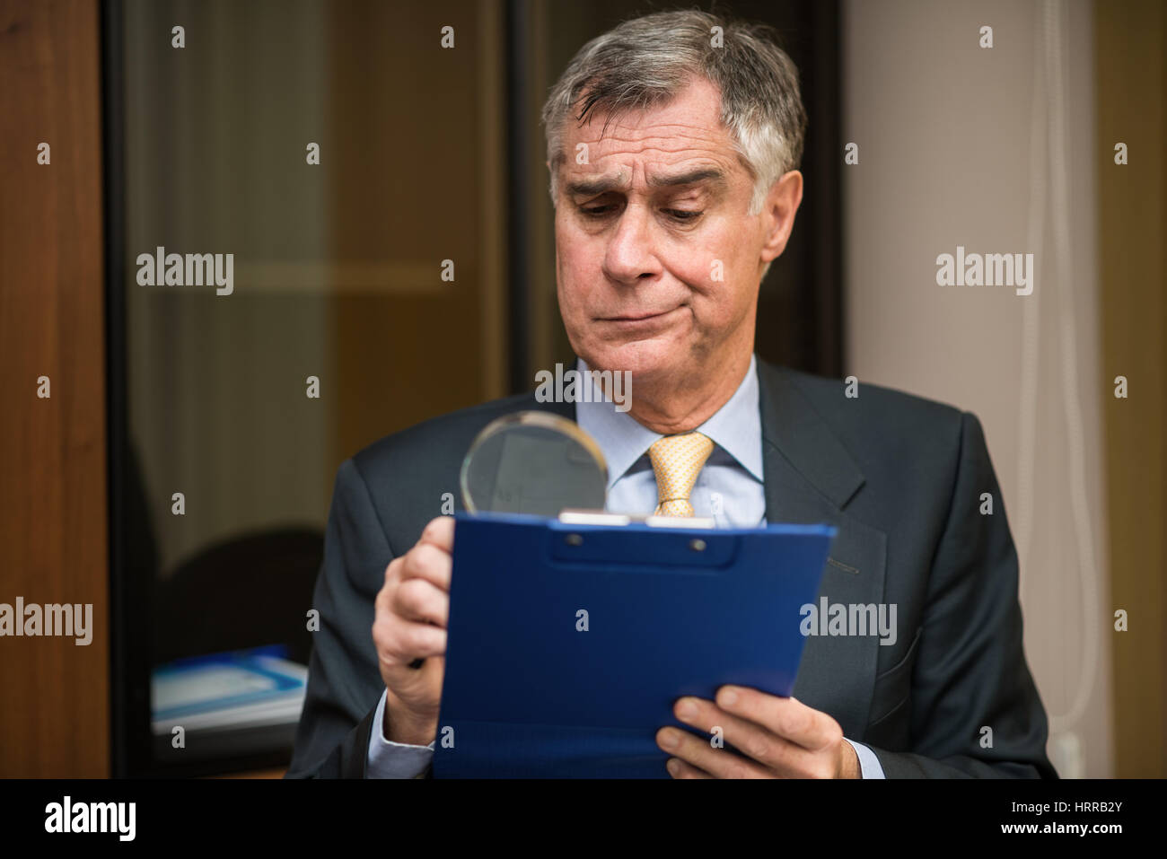 Businessman using a magnifying glass to read a document Stock Photo