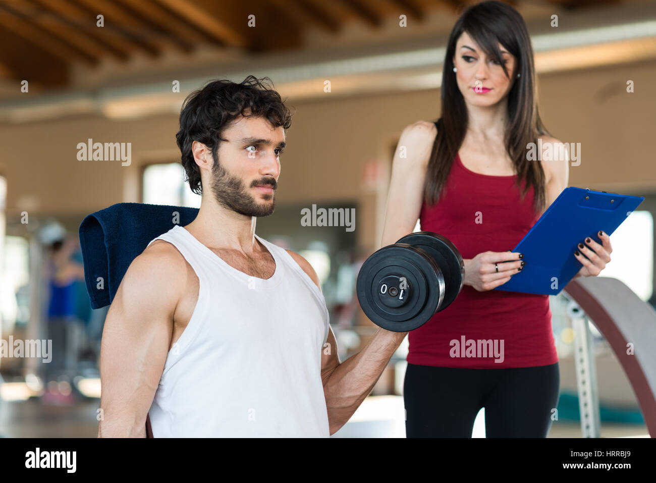 Female personal trainer looking at an athlete doing an exercise Stock