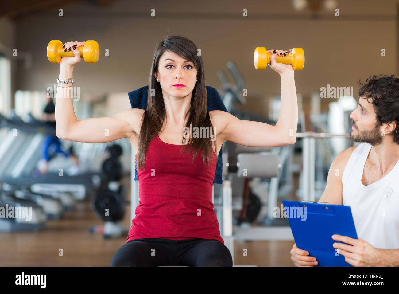 Personal trainer looking at a training woman in the gym Stock Photo - Alamy
