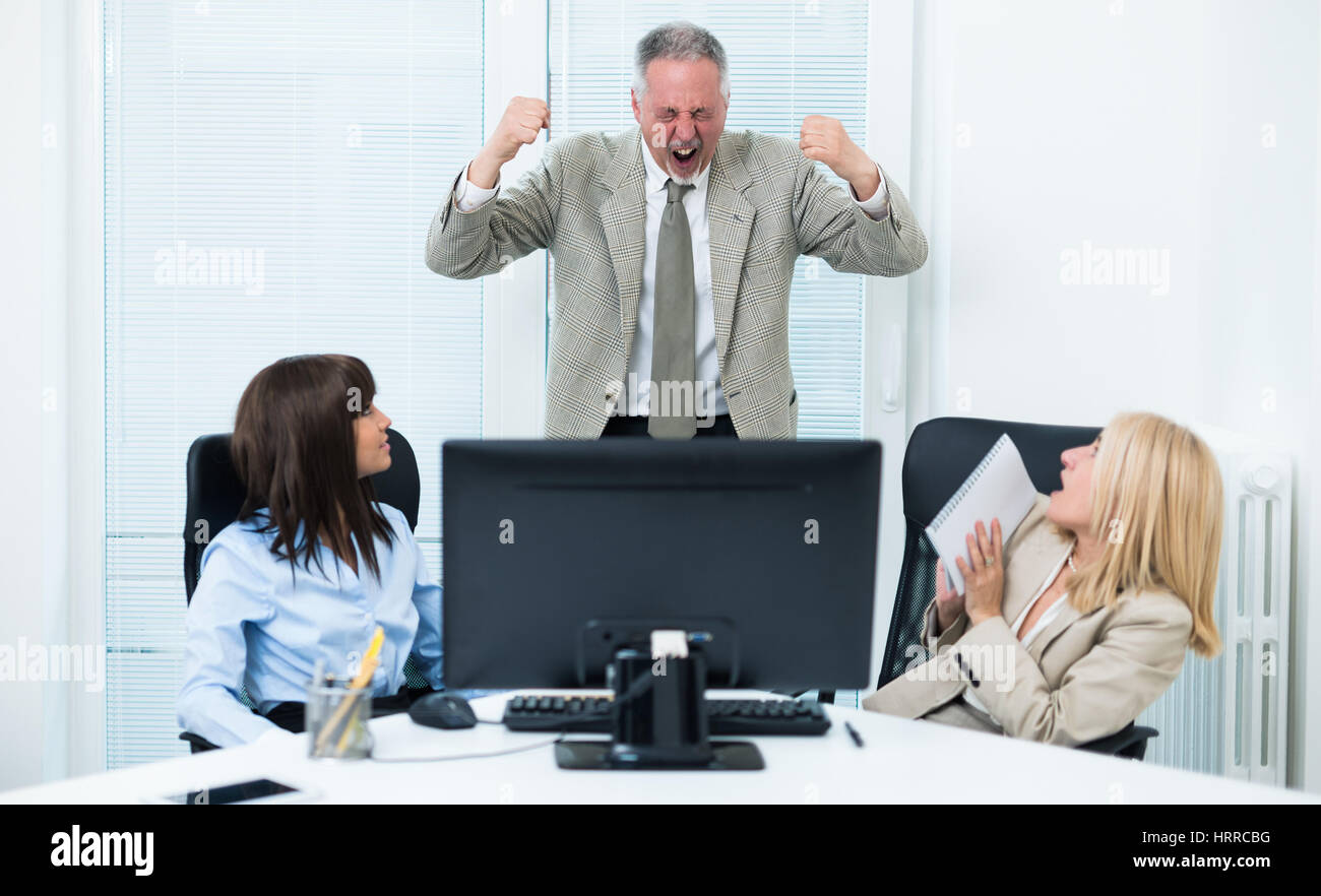 Angry businessman yelling at his colleagues in a bright office Stock Photo