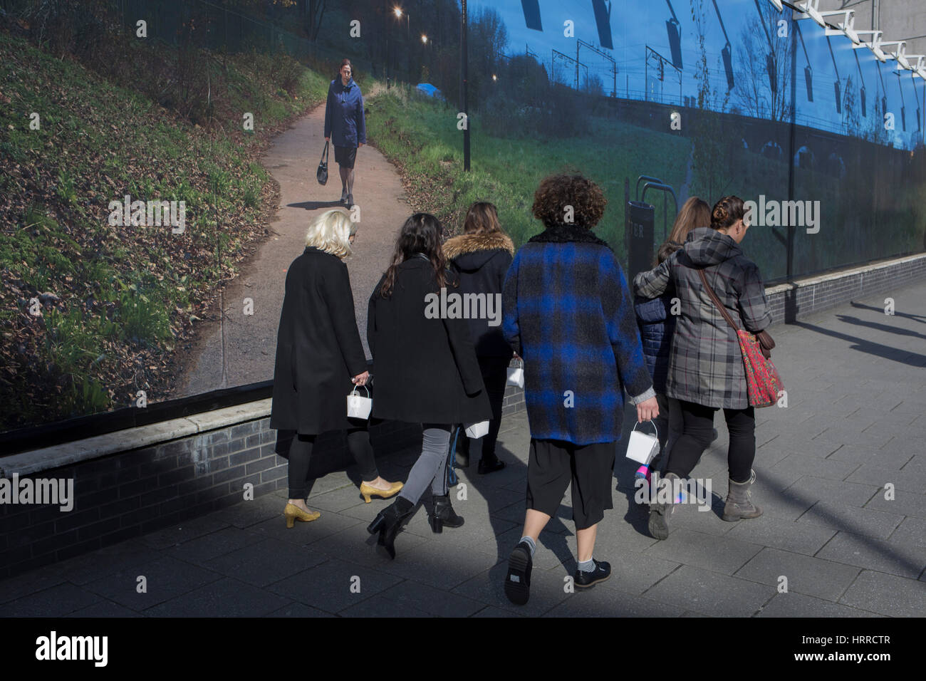 Lunch box-carrying women pass the artwork by British-Iranian photographer and film director, Mitra Tabrizian, on 2nd March 2017, in The Cut, London borough of Southwark, England. Stock Photo