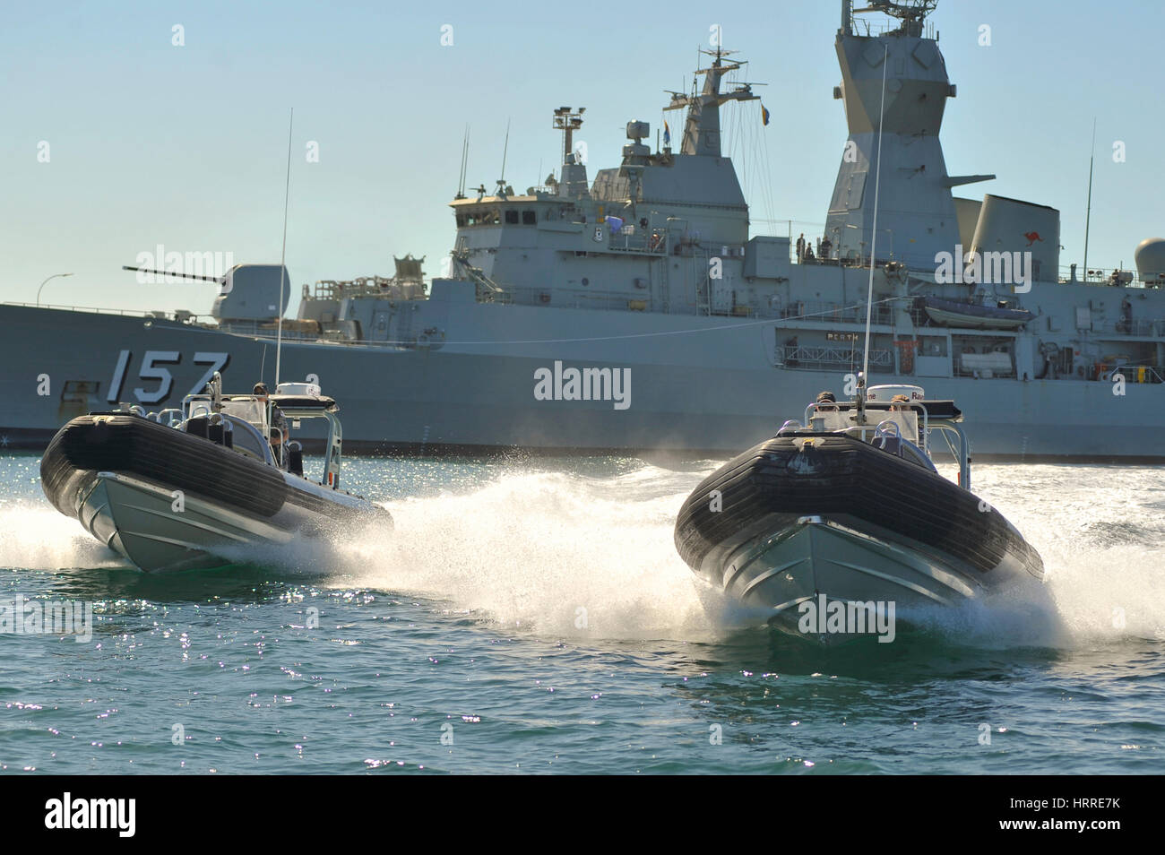 Naval RHIB's leaving frigate, head-on shot with wakes Stock Photo